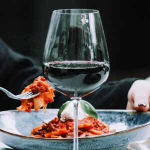 Glass of Italian red wine with pasta al ragù – Classic food and wine pairing.