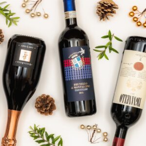 Three Italian red wines with festive Christmas decorations, including pinecones and greenery, flat lay style.