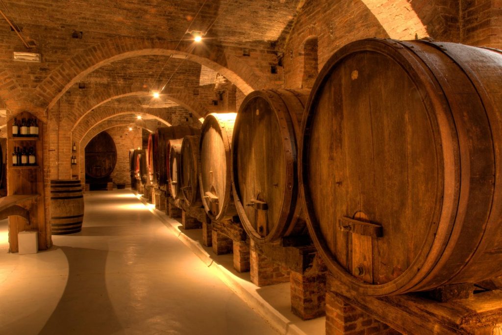 Interior of Massimo Leone Winery, featuring wooden barrels in a rustic setting.