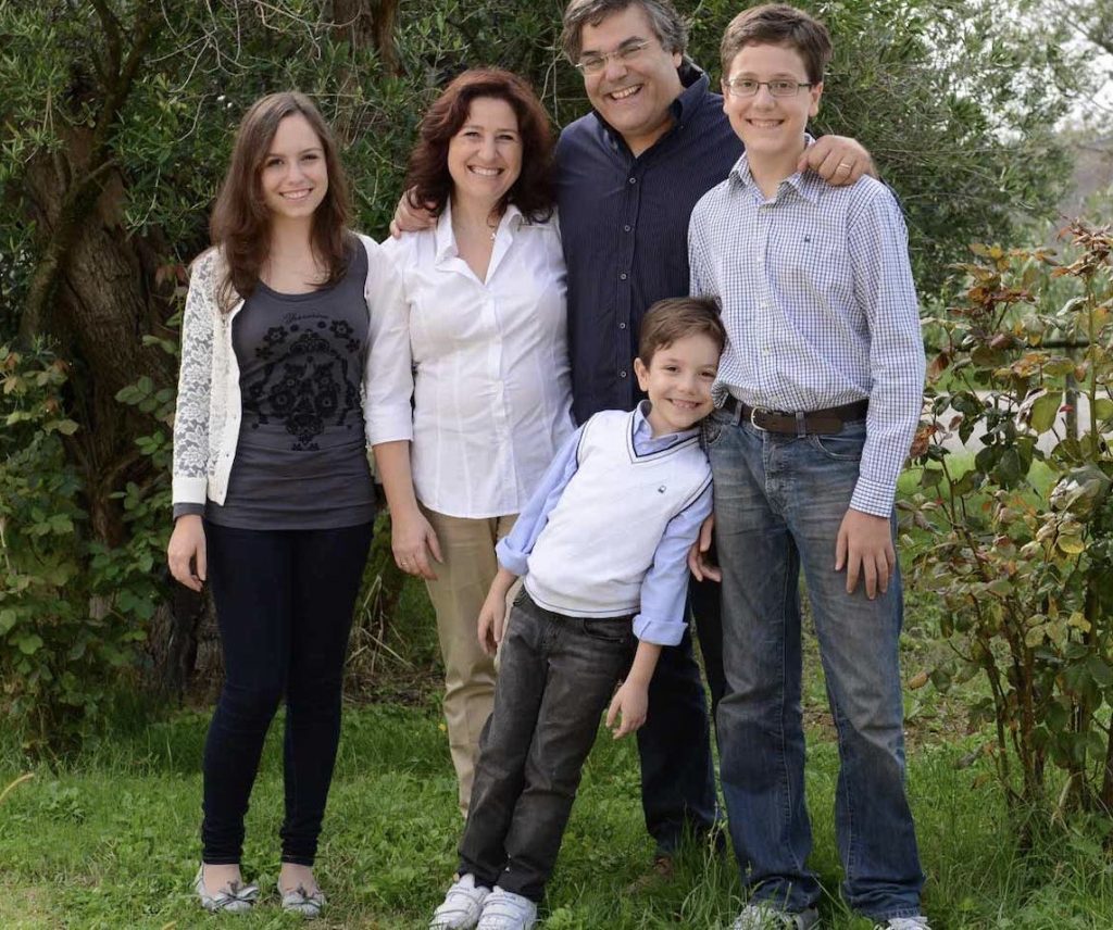The Giusti family standing together in their vineyard, surrounded by lush vines in the Marche region.